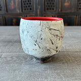 side view of layered slip on a Red stoneware mug with matte glaze interior and red cherry blossom design, no glaze on outside, instead it is sanded smooth. 